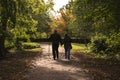 Man leaning on a wooden crutch walking hand in hand with woman in the Hexthorpe park.