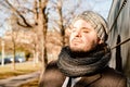 Man leans against a fence outside and enjoys the sun in the cold season. Contemplation, serenity and relaxing concept