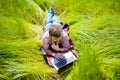 Man learns, working on laptop lying on meadow. mobile Internet in rural