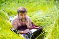 Man learns, working on laptop lying on meadow. mobile Internet in rural