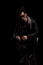 Man in leather jacket and boots wearing sunglasses sitting Royalty Free Stock Photo