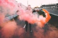 Man in a leather jacket standing at the street with smoke bomb. Colorful portrait of european teenager with red smoke bomb Royalty Free Stock Photo