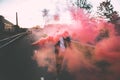 Man in a leather jacket standing at the street with smoke bomb. Colorful portrait of european teenager with red smoke bomb Royalty Free Stock Photo