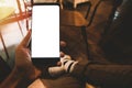 Man left hand holding mockup blank white screen cell phone and He wears sneakers with cross-legged sitting position, sit on the Royalty Free Stock Photo