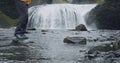 Man legs crop crossing the river of Stjornarfoss waterfall near Kirkjubaejarklaustur at Iceland