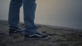 Man legs in sneakers standing on sea shore. Guy in blue jeans posing on beach Royalty Free Stock Photo