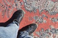 Man legs standing on turkish oriental carpet texture.