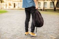 Man legs in yellow sneakers, denim shirt, black jeans at university campus. Back view of stylish man stand with book, waiting. Leg Royalty Free Stock Photo