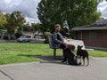 Man leisurely sitting on a park bench with two dogs, enjoying the nice weather at downtown Kirkland Marina