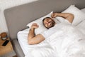 man leisurely wakes up stretching arms in bed at home