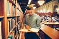 Man in the library reading room took the book from the shelf and reading