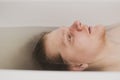 A man lies in a bathtub filled with water and looks up indifferently. Fatigue after a working day is expressed on the face. Photo