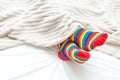 A man lies in a bed under a rug in socks of rainbow colors. LGBT concept. Close-up