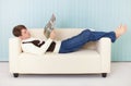 Man lies comfortably on sofa with a magazine Royalty Free Stock Photo