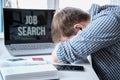 Man lies face down on table next to laptop. Unemployment, crisis, stress, job loss. Looking for remote work at home.Mobile phone, Royalty Free Stock Photo