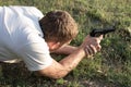 A man lies on the grass with a gun in his hands, preparing to shoot. Leisure and hobbies Royalty Free Stock Photo