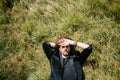 Man lies on the green grass covering his face with his hand from the sun Royalty Free Stock Photo