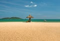 A man lifeguard, sitting under an umbrella of palm leaves on a deserted beach of Hainan Island. Royalty Free Stock Photo