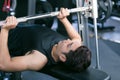 Man lifting dumbbell weights while lying down in gym.