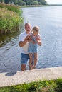 A man lifts a giggling child by the lake a joyous, sunny day. Captures family fun, summer activities, used for health Royalty Free Stock Photo