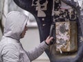 A man in a light jacket in a hood is calling an old street payphone Royalty Free Stock Photo