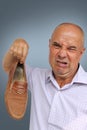 A man in a light shirt holds a brown male shoe in his hand, a grimace of disgust from the bad smell on his face, close-up, copy