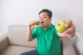 Man likes junk food better than healthy fresh fruit Royalty Free Stock Photo