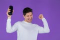 Man listening to music by wireless portable speaker - modern sound system. Young guy dancing, enjoying at purple studio Royalty Free Stock Photo