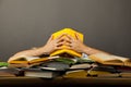 Man littered with pile of colorful books, his hands cover his face with a Yellow book Royalty Free Stock Photo