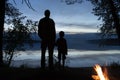 A man and a little boy father and son are holding hands while standing on the shore and admire the reflection of evening clouds Royalty Free Stock Photo