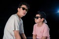 Man and little boy with sunglasses sit looking camera on dark studio background , asian family Royalty Free Stock Photo