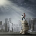 Man with little child standing on books stack