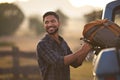 Man Loading Backpack Into Pick Up Truck For Road Trip To Cabin In Countryside Royalty Free Stock Photo