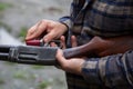 A man loading a red shotgun shell into the magazine of his gun