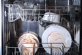 A man loads dirty dishes, plates, spoons, forks, cutlery into dishwasher tray Royalty Free Stock Photo