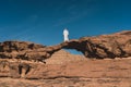 A man with local Arab dress standing on natural rock bridge in Wadi Rum desert, Jordan, Arab