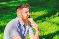 Man with long beard eats ice cream, while sits on grass. Bearded man with ice cream cone. Man with beard and mustache on Royalty Free Stock Photo