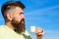 Man with long beard enjoy coffee. Coffee gourmet concept. Man with beard and mustache on strict face drinks coffee, blue