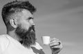 Man with long beard enjoy coffee. Coffee gourmet concept. Man with beard and mustache on strict face drinks coffee, blue