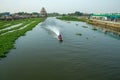 A man with long boat, with a small motor driving a propeller at the end of a long shaft in the canal Royalty Free Stock Photo