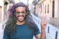 Man with long colourful hairstyle giving peace sign