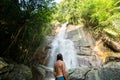 Man with a long hair is enjoy in lagoon of huge tropical waterfall in jungle. Travel concept.