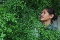 A man with a Long hair and a mustache peeking out from the bushes of Terminalia ivorensis Chev bedew