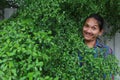 A man with a Long hair and a mustache peeking out from the bushes of Terminalia ivorensis Chev bedew