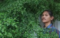 A man with a Long hair and a mustache peeking out from the bushes of Terminalia ivorensis Chev bedew