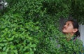 A man with a Long hair and a mustache peeking out from the bushes of Terminalia ivorensis Chev bedew