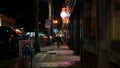 Man look like homeless walking, city street walkway at night. Male person on sidewalk California USA Royalty Free Stock Photo