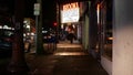 Man look like homeless walking, city street walkway at night. Male person on sidewalk California USA