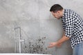 Man looking at affected with mold wall in bathroom Royalty Free Stock Photo