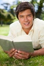 Man looking ahead while reading a book as he lies on grass Royalty Free Stock Photo